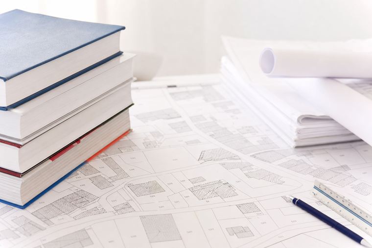 Un uomo vestito di bianco legge con attenzione un libro aperto tra le mani.